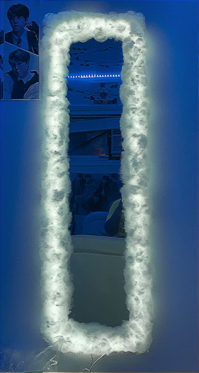 a large white mirror sitting on top of a wall next to a blue light fixture