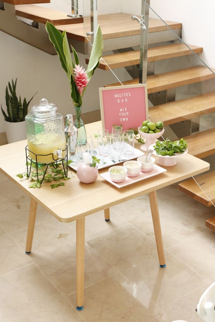 a wooden table topped with plates and cups filled with food next to a stair case