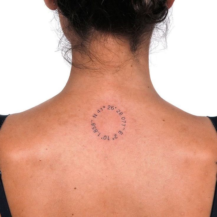 the back of a woman's neck with an inscription written on her left shoulder