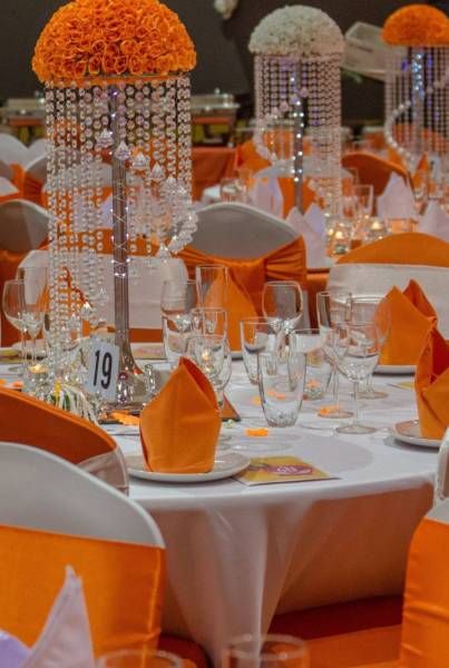 an orange and white wedding set up with crystal chandelier, candles and centerpieces