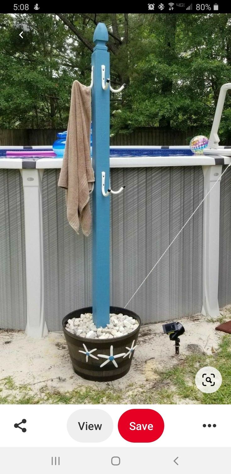 an outdoor pool with a blue pole attached to it and some sand in the ground