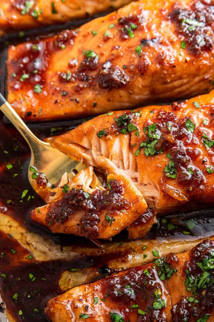 a pan filled with chicken covered in bbq sauce and garnished with parsley