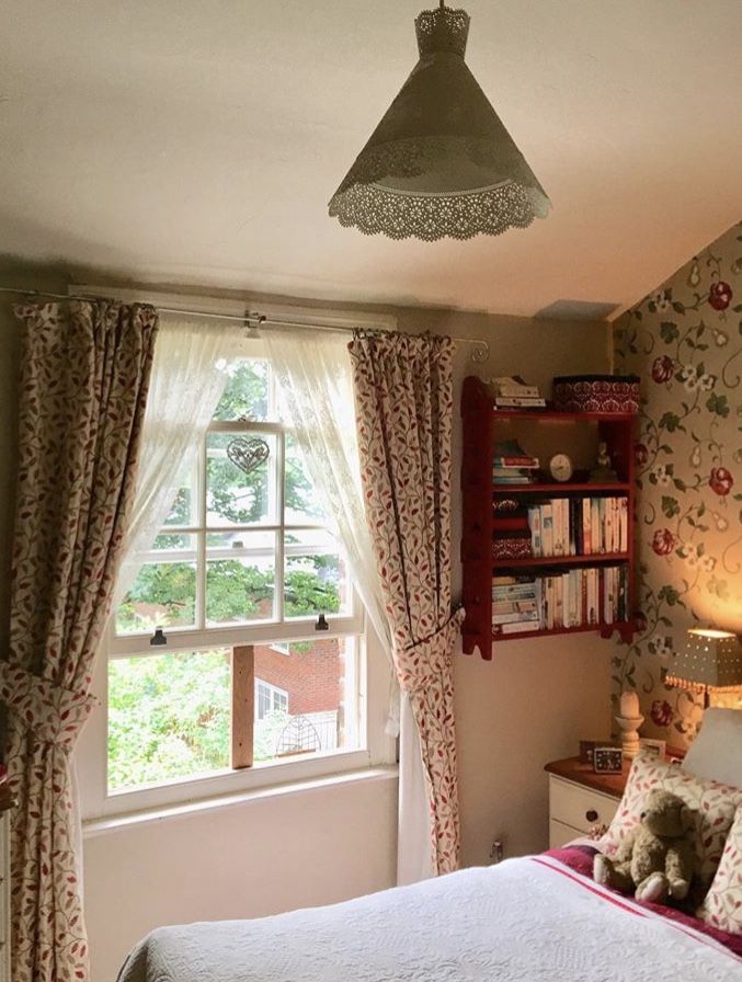 a bed sitting under a window next to a book shelf