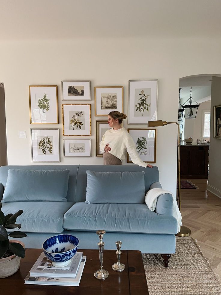 a woman sitting on top of a blue couch in a living room next to a coffee table