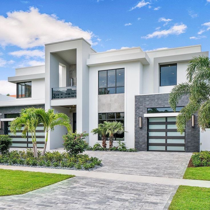 a large white house with palm trees in the front yard and landscaping on either side