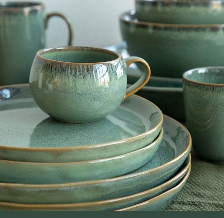 a stack of green cups and saucers sitting on top of each other