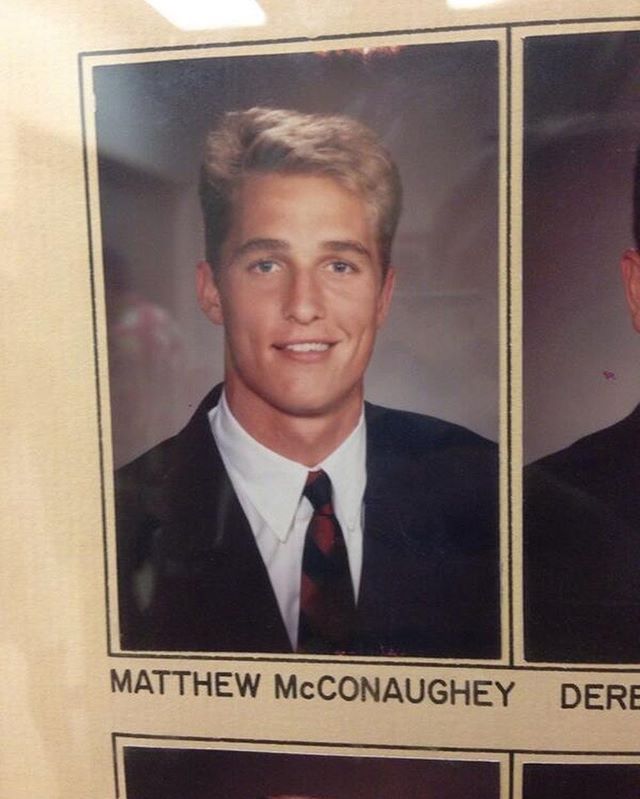 two men in suits and ties are smiling for the camera, one is missing his tie