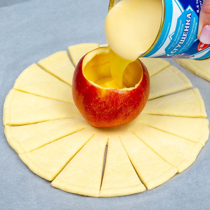 an apple being poured into a can of yogurt on top of sliced apples