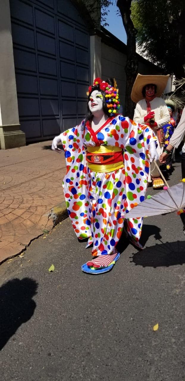 two clowns are walking down the street with umbrellas