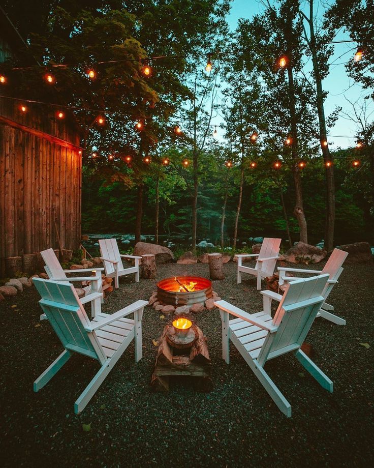 a fire pit surrounded by lawn chairs and string lights