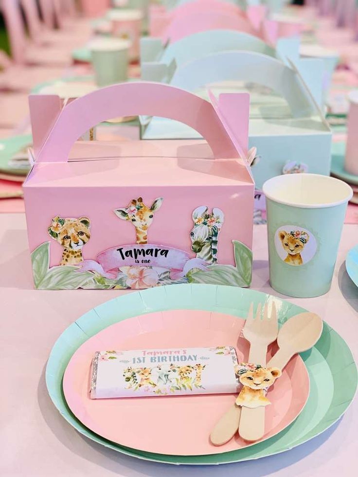 a pink lunch box sitting on top of a table next to plates and utensils