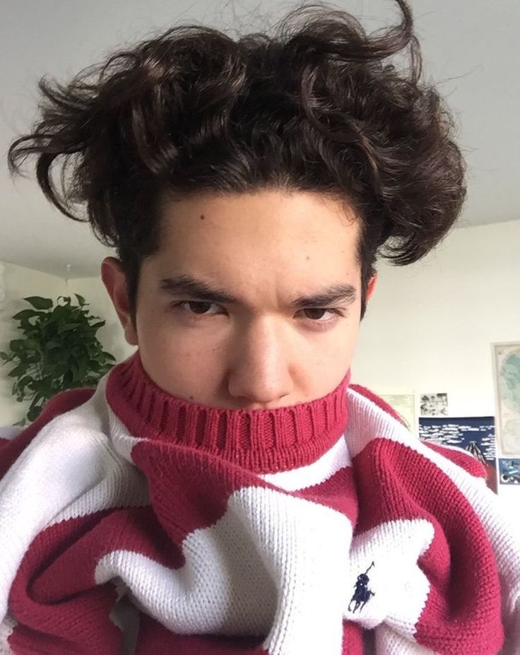 a man wearing a red and white sweater has his hair in the air as he stares at the camera