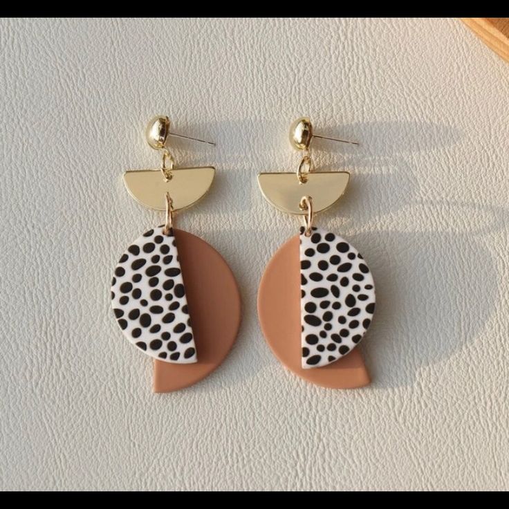 a pair of earrings sitting on top of a white table next to a wooden bowl