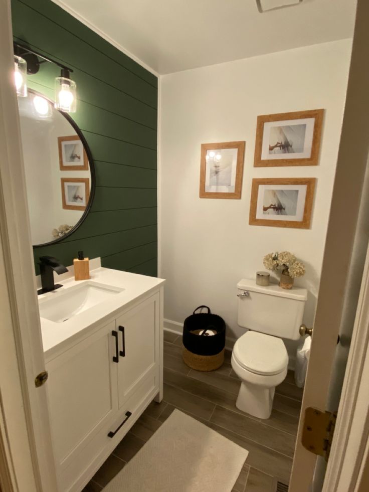 a white toilet sitting next to a sink in a bathroom under a large round mirror