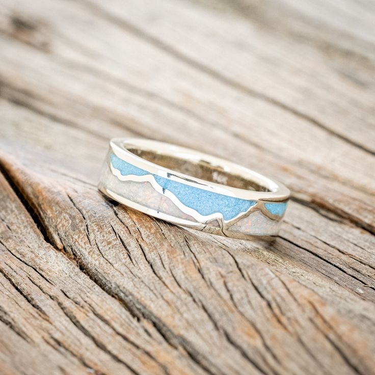 a silver ring sitting on top of a wooden table next to a piece of wood