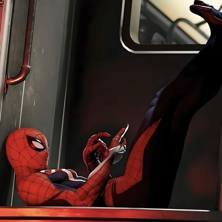 spider - man sitting on the train looking at his cell phone