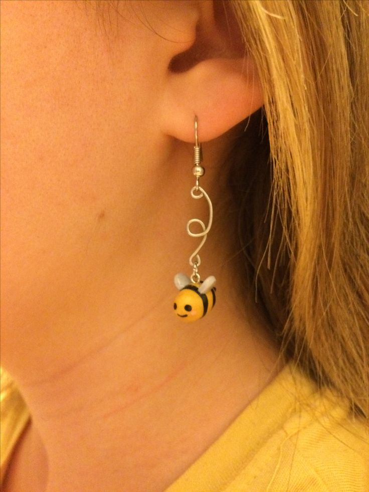 a close up of a person wearing some kind of earring with a bee on it