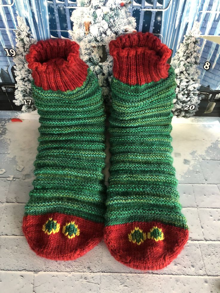 a pair of green and red knitted slippers sitting on top of a tiled floor