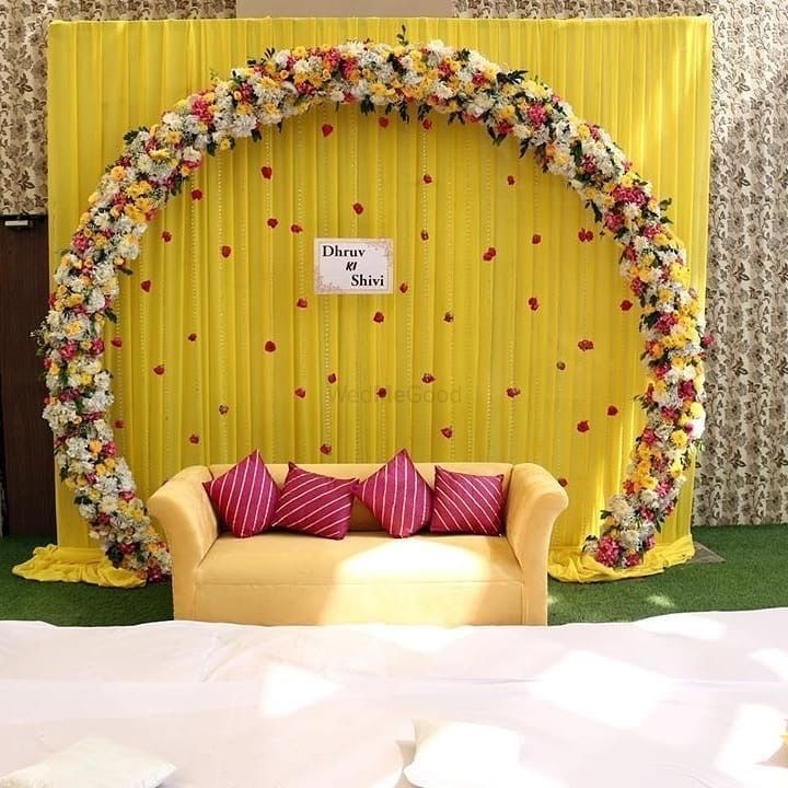 a couch sitting in front of a yellow backdrop with flowers on it and a sign that says welcome to you