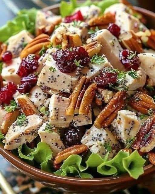 a salad with chicken, cranberries and pecans in a bowl on a table