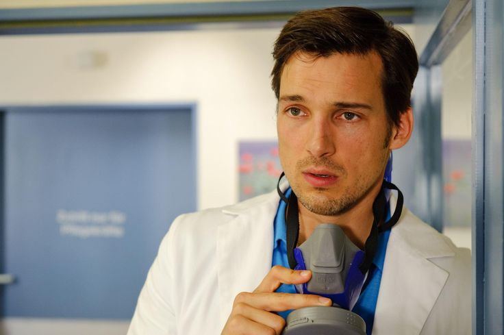 a man in a lab coat is holding a camera and looking at the camera while wearing a stethoscope