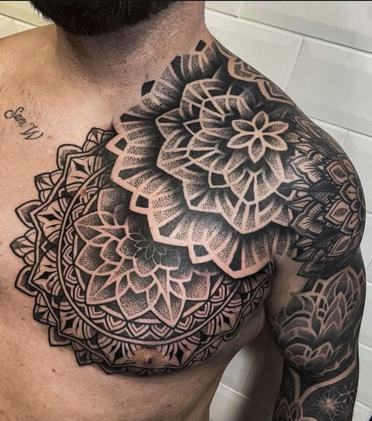 a man's chest with an intricate tattoo design on the top half of his body