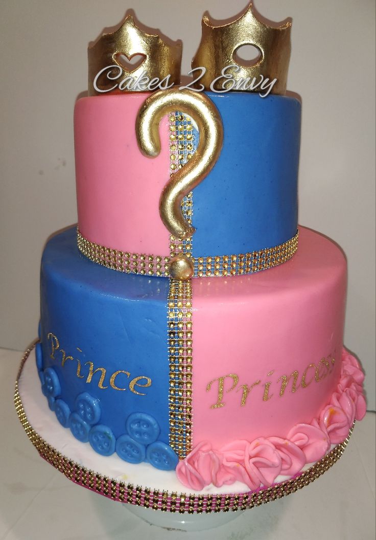 two tiered cake with pink, blue and gold frosting decorated with princess crowns