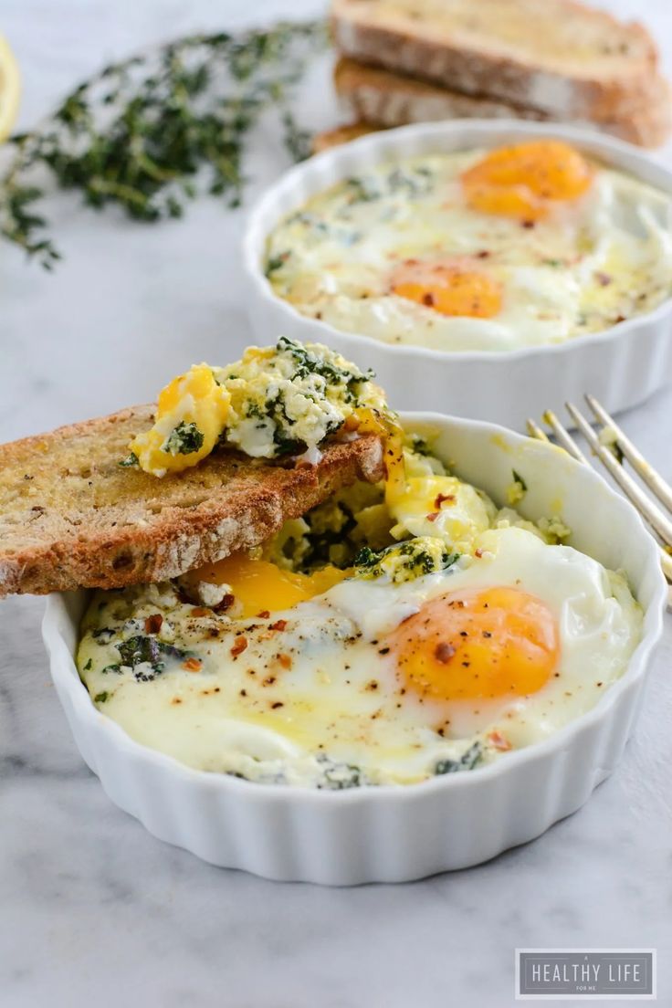 two bowls filled with eggs and toast on top of a white counter next to slices of bread