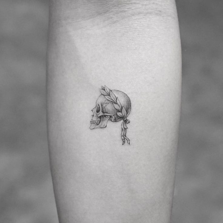 a small skull tattoo on the left calf's lower leg, with a flower in its hair