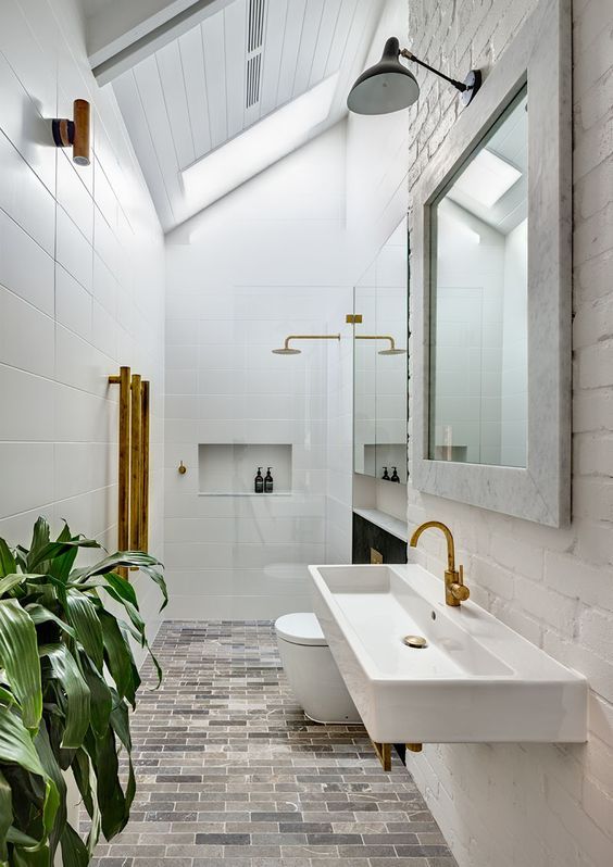 a white bathroom with two sinks and a large mirror above the bathtub is surrounded by greenery