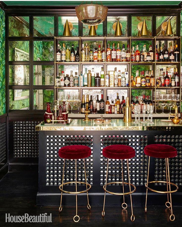 a bar with three stools in front of it and several bottles on the shelves