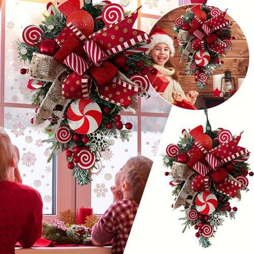 a christmas wreath with candy canes hanging from it's side and two children looking out the window