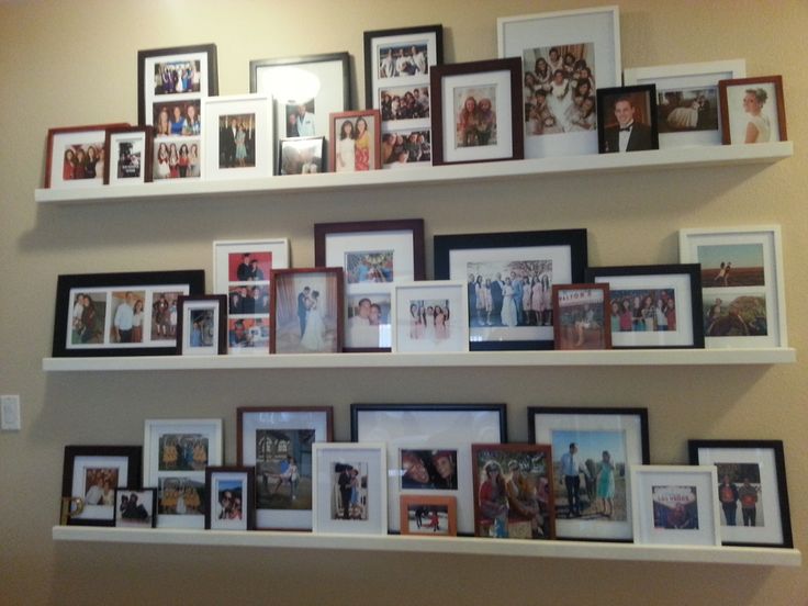 a wall filled with lots of pictures and framed photos on top of white shelving