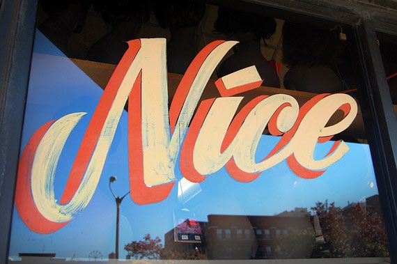 a close up of a store window with the word nice written in red and white