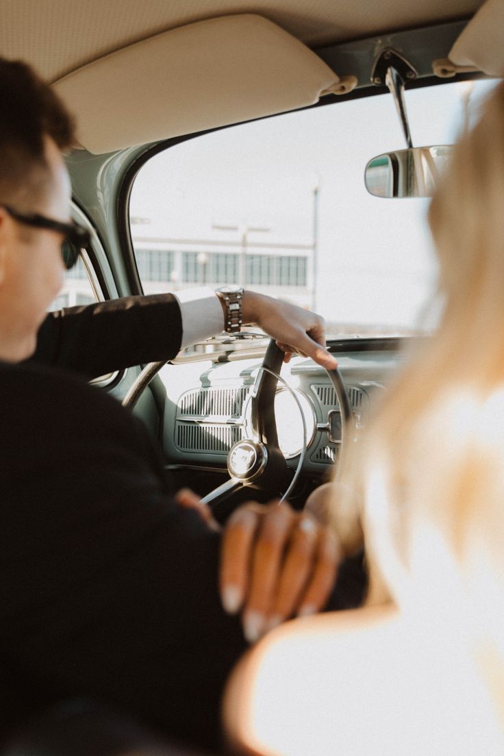 a man and woman sitting in the driver's seat of a car looking at each other