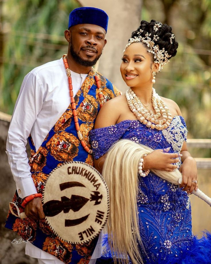 a man and woman dressed in traditional african garb posing for the camera with their arms around each other