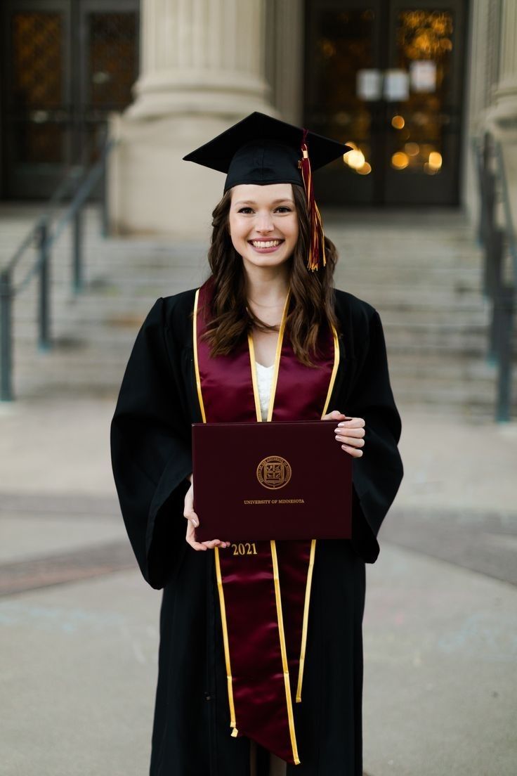 a woman wearing a graduation gown and holding a diploma in front of a building with columns