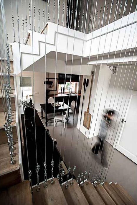 a person walking down the stairs in a house with glass railings on each side