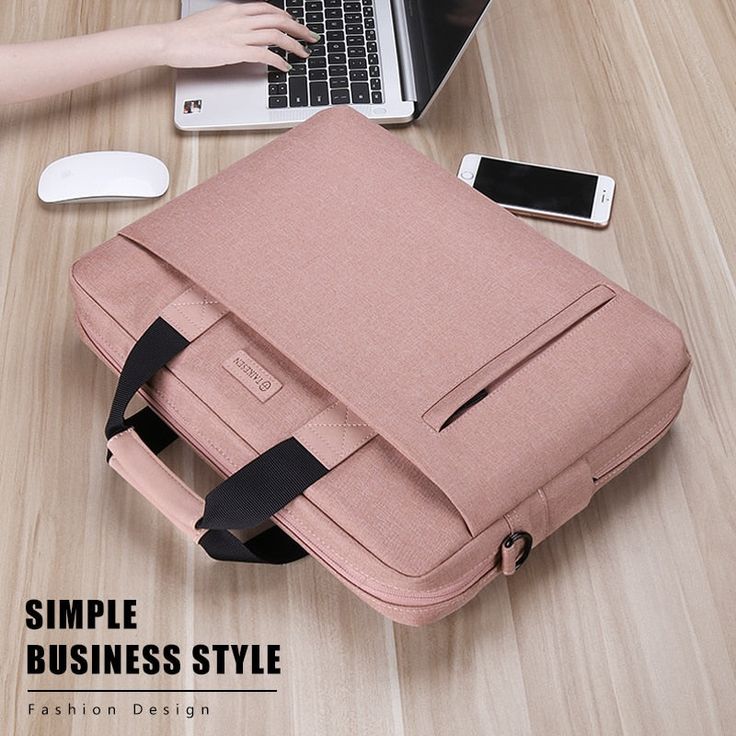 a pink laptop bag sitting on top of a wooden table next to a woman's hand