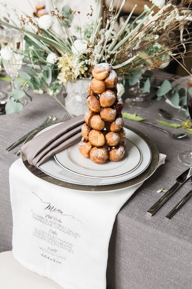 a stack of doughnuts sitting on top of a white plate next to a vase filled with flowers