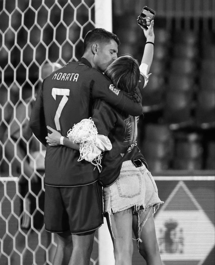 a couple of people that are standing in front of a goalie net with their arms around each other