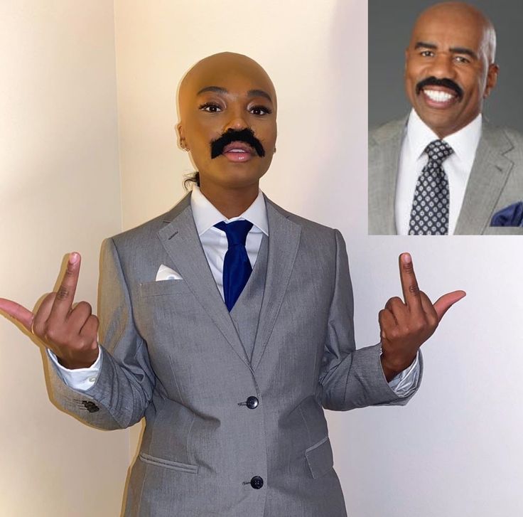 a man wearing a suit and tie making the vulcan sign with his hands while standing in front of a white wall