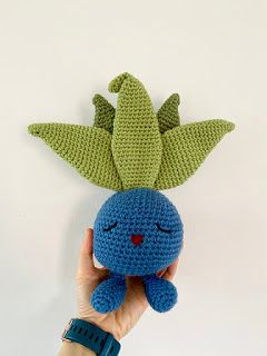 a hand holding a crocheted blue stuffed animal