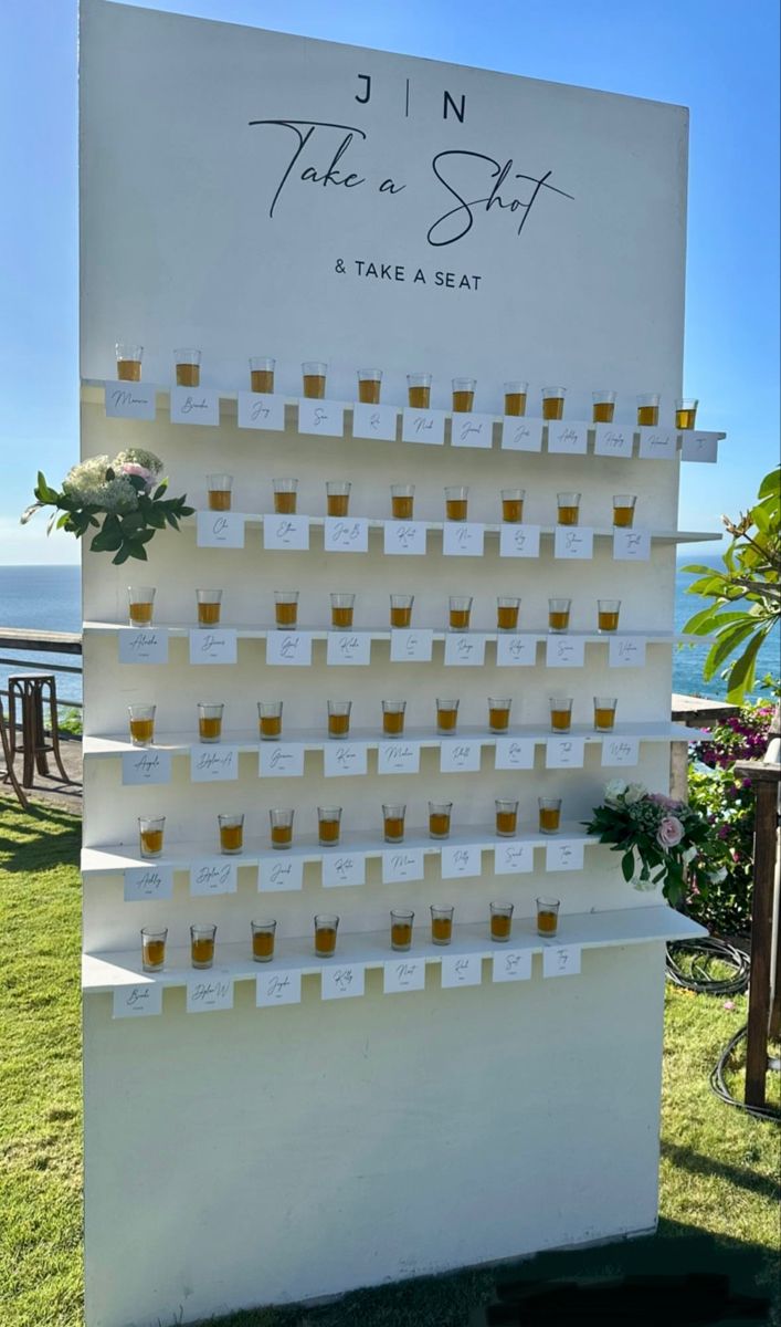 there is a sign with cups on it that says take a seat in front of the ocean