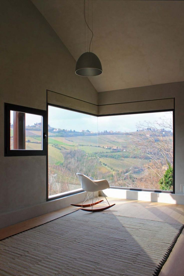 an empty bedroom with a large window looking out onto the valley outside, and a bed in the foreground