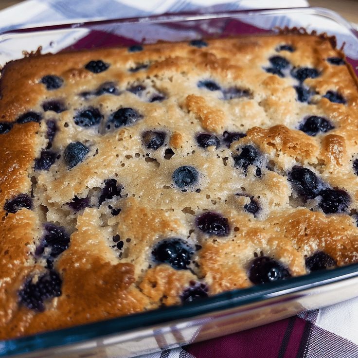 a casserole dish with blueberries in it on a checkered table cloth