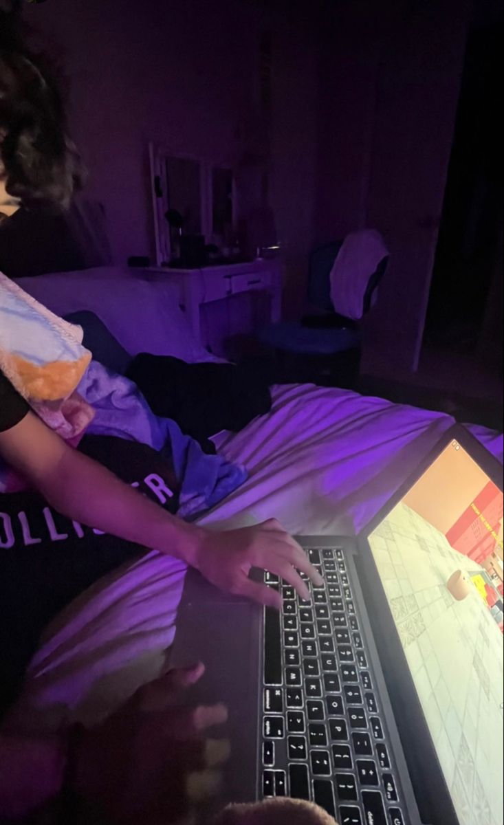 a person laying in bed with a laptop on their lap and looking at the screen