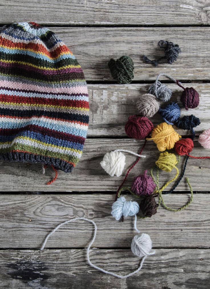 several balls of yarn are laying next to each other on a wooden surface, including one ball of yarn and two skeins of yarn