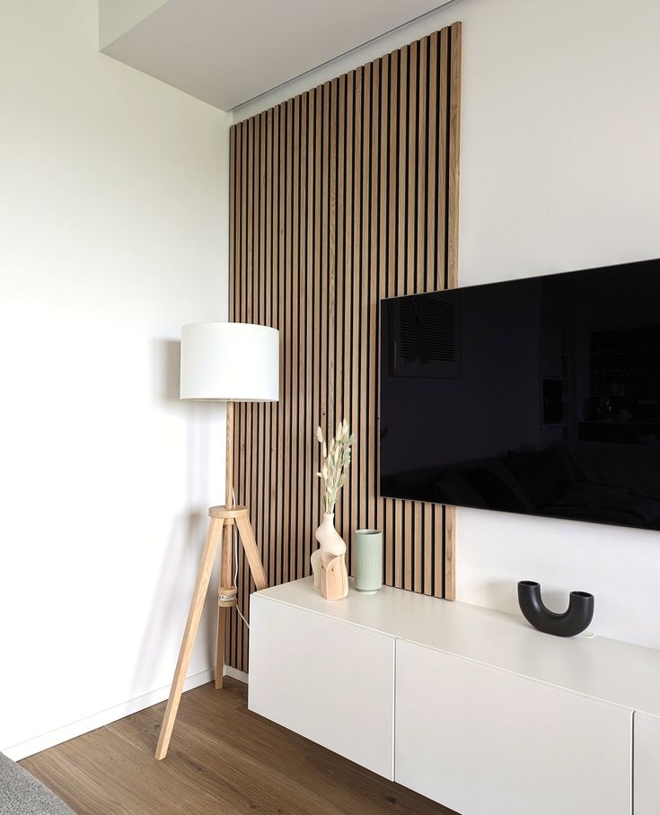 a flat screen tv sitting on top of a white entertainment center next to a lamp