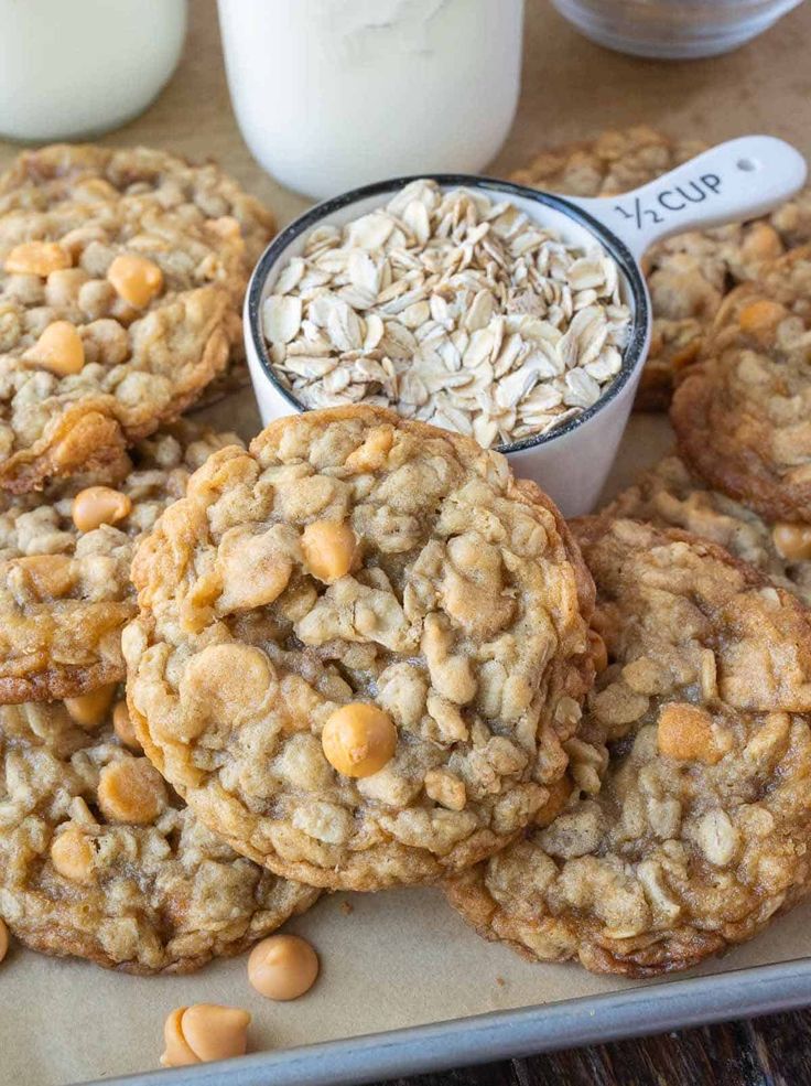 cookies and oatmeal are on a baking sheet with milk in the background